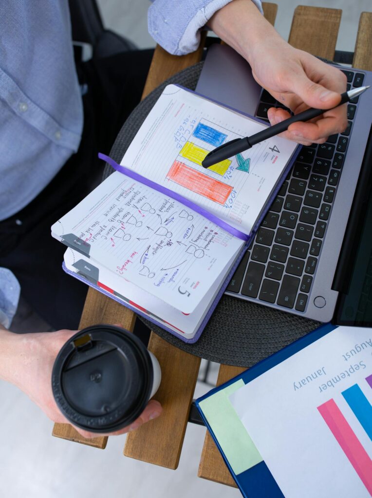 Man working with notes and laptop over a coffee break, analyzing charts.